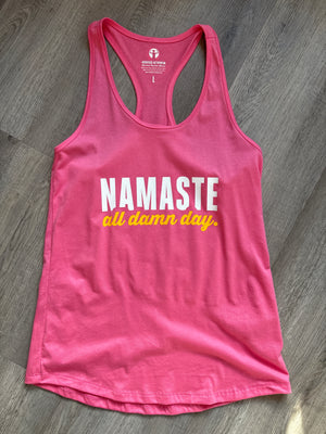 Pink tank top with 'NAMASTE all damn day' text on a wooden surface