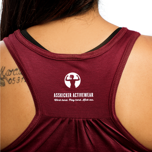 Back view of a maroon coloured gym tank for woman. Includes the Asskicker logo with a strong woman icon and work hard play hard kick ass saying.