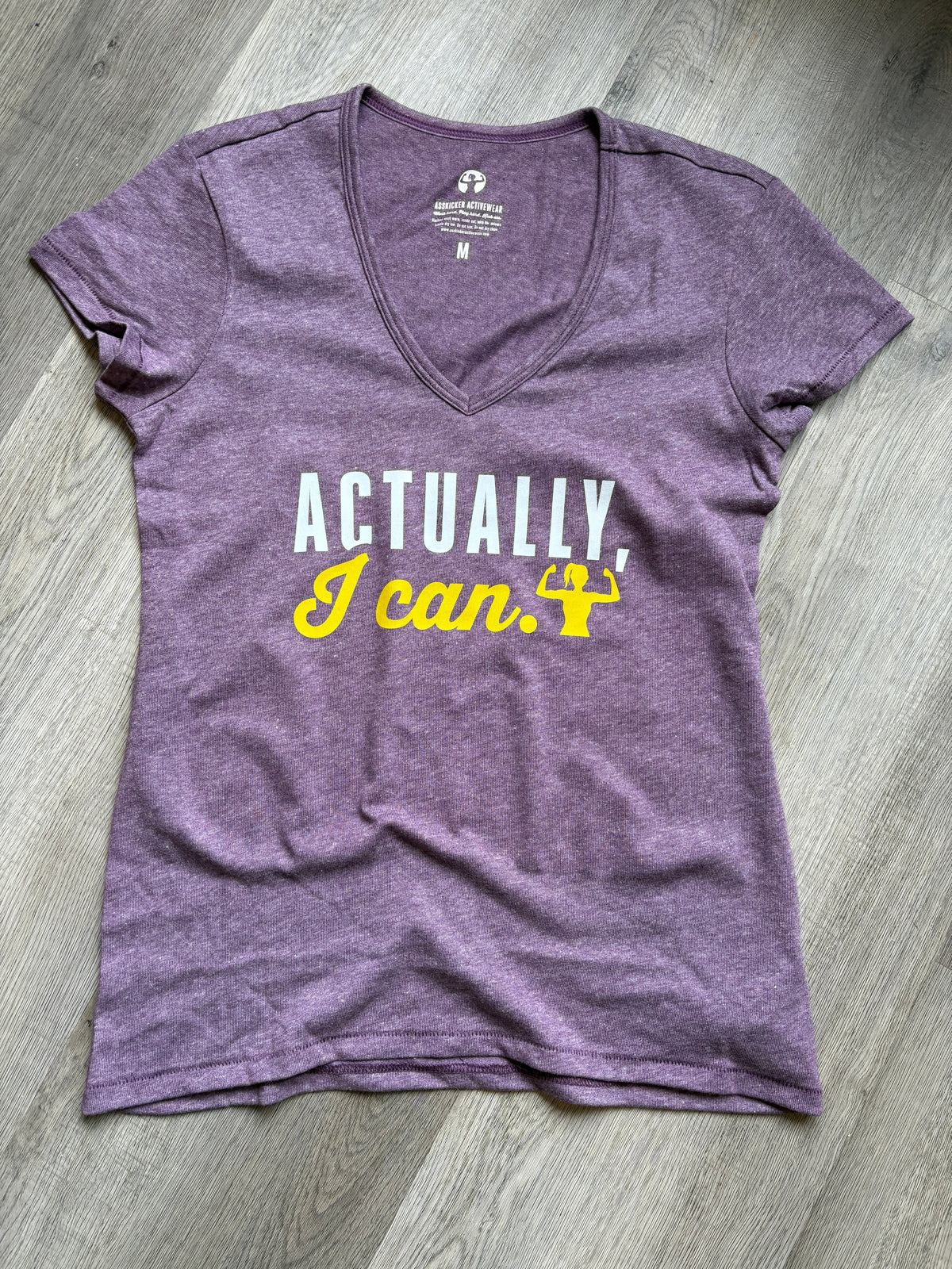 Purple t-shirt with text on a wooden floor