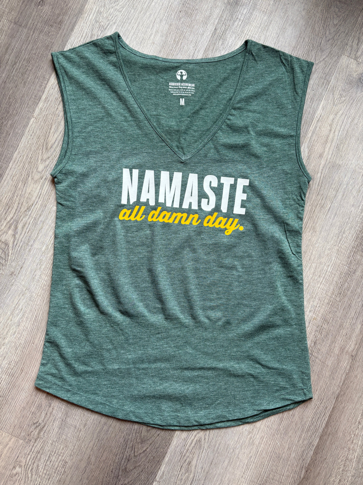 Green tank top with 'Namaste all day' text on a wooden floor