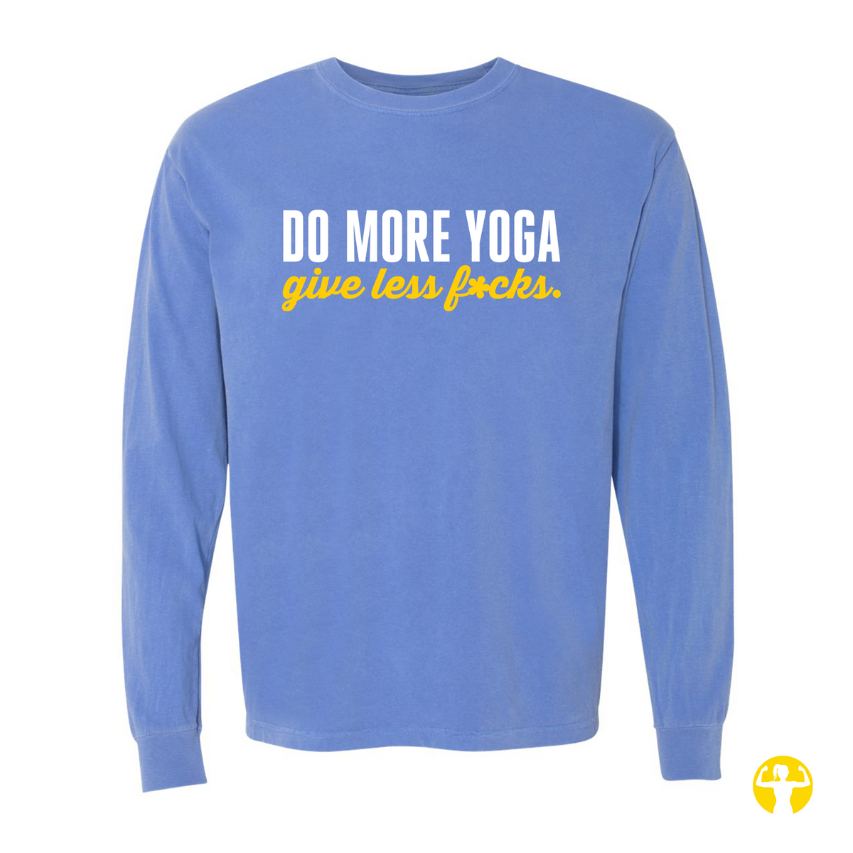 Flat lay view of a washed periwinkle Flo Blue Comfort Colors long sleeve shirt featuring the text 'Do More Yoga, Give Less F*cks' printed across the chest in bold white block lettering and bright yellow script, on a light beige background.