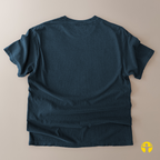 A dark teal blue short-sleeve t-shirt laid flat on a light beige background, showing the back side with natural fabric folds.