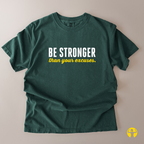 A dark green short-sleeve t-shirt laid flat on a light beige background, featuring the text 'BE STRONGER' in white and 'than your excuses.' in yellow across the chest.