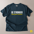 A dark navy blue t-shirt laid flat on a light beige background, featuring the text 'BE STRONGER than your excuses.' printed on the chest in white and yellow.