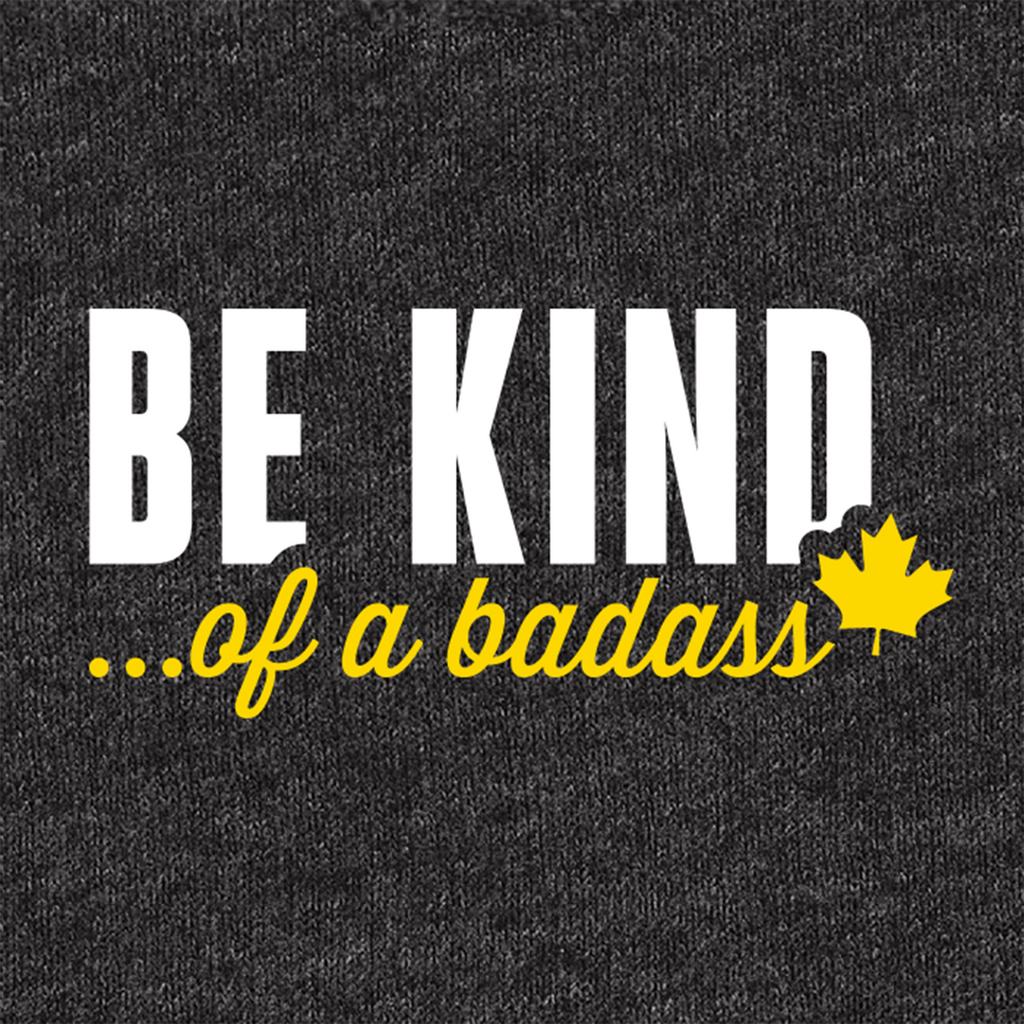 A close-up of a dark heather gray fabric surface with printed text 'BE KIND... of a badass"