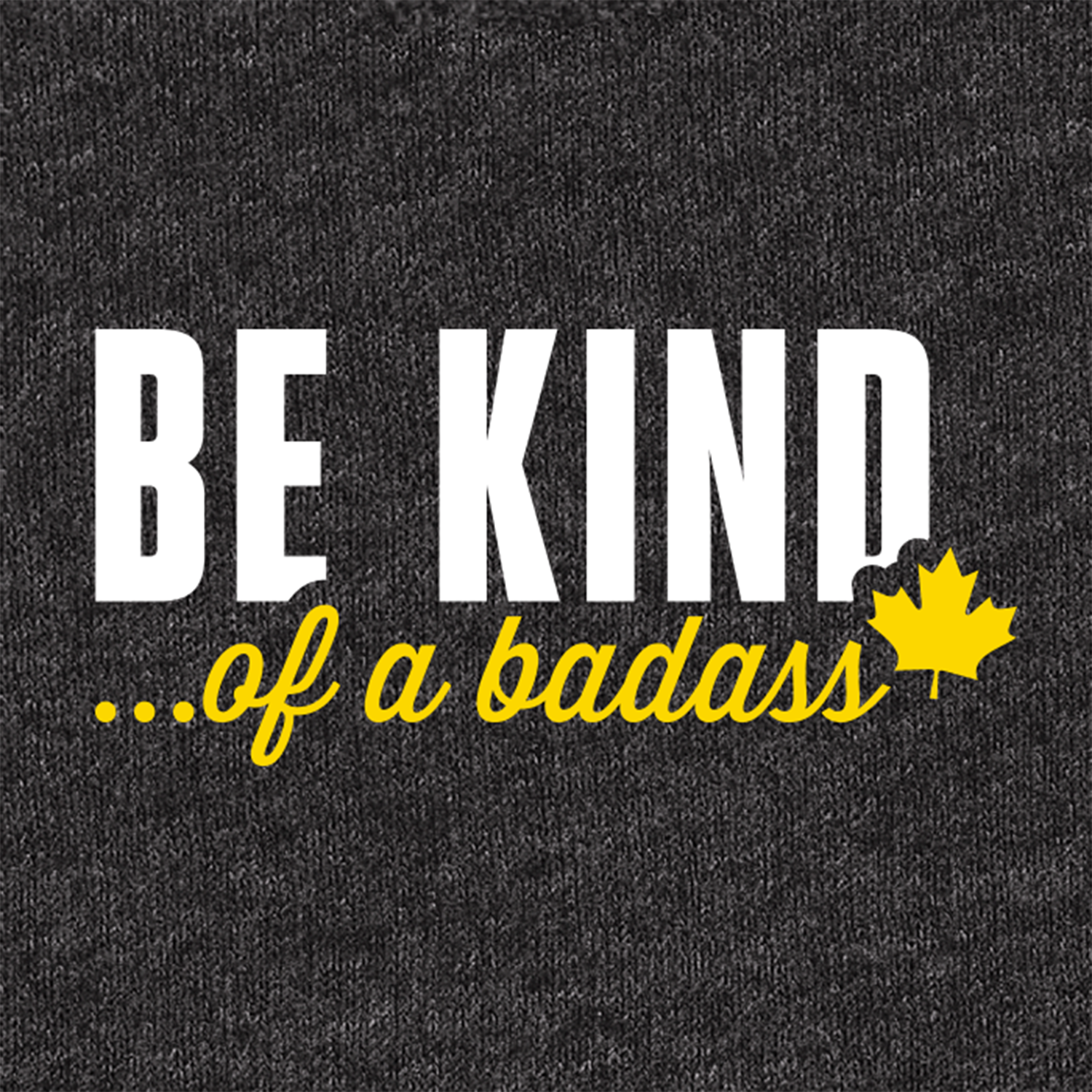 A close-up of a dark heather gray fabric surface with printed text 'BE KIND... of a badass"