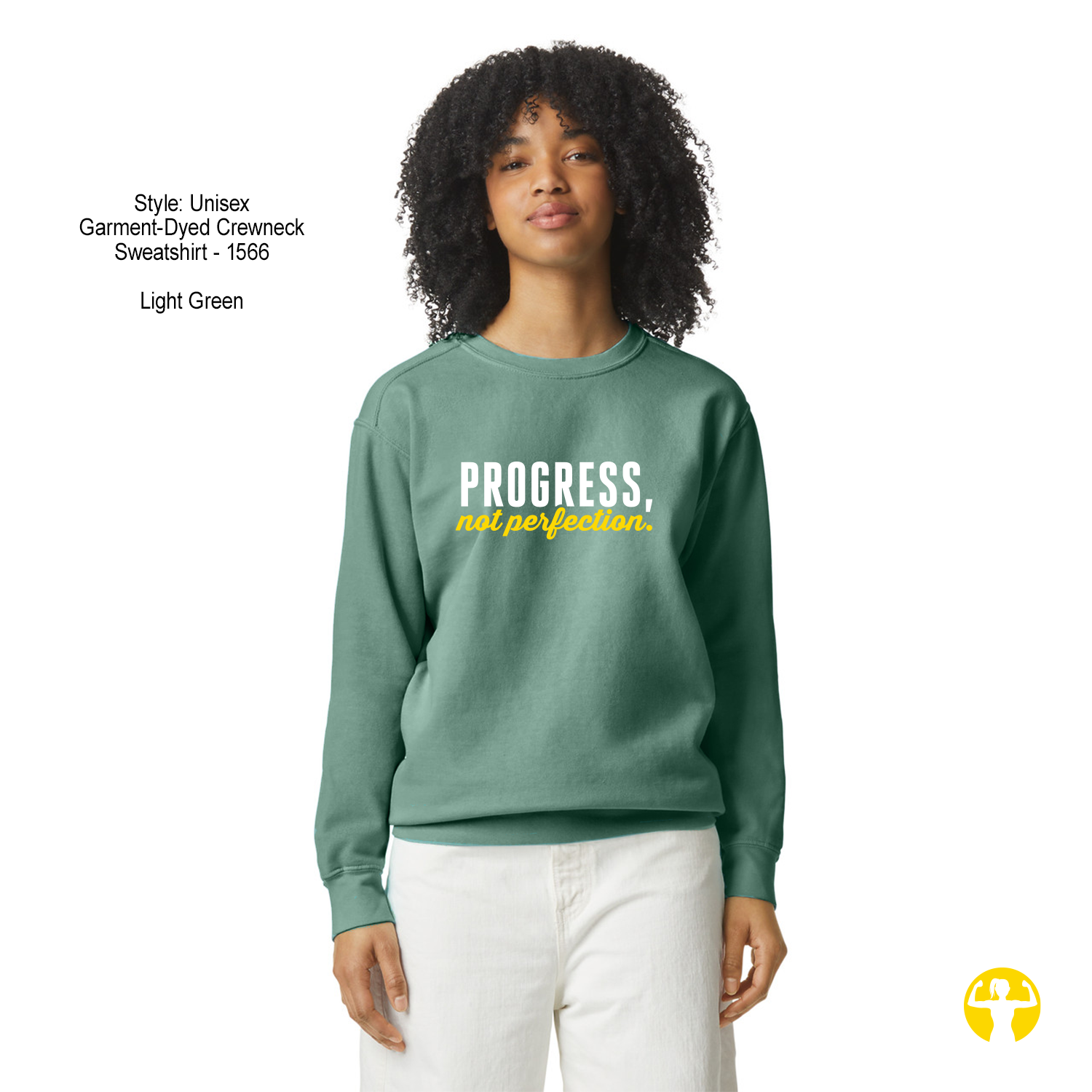 A model wearing a light green crewneck sweatshirt with the text 'PROGRESS, not perfection.' printed on the chest in white and yellow.