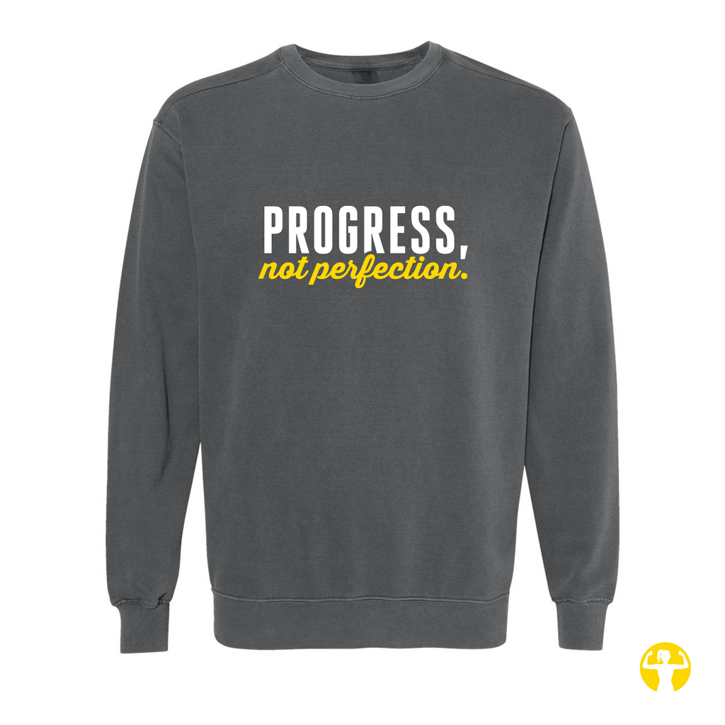 A dark gray crewneck sweatshirt with the text 'PROGRESS, not perfection.' printed on the chest in white and yellow, shown against a plain white background.