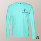 A mint green long-sleeve t-shirt with a black graphic on the left chest, displayed on a neutral beige background. The graphic features a small illustration of a painting easel and camping tent with the text  'Celebrating Canadian Landscapes' and 'The Canvas Collection'.