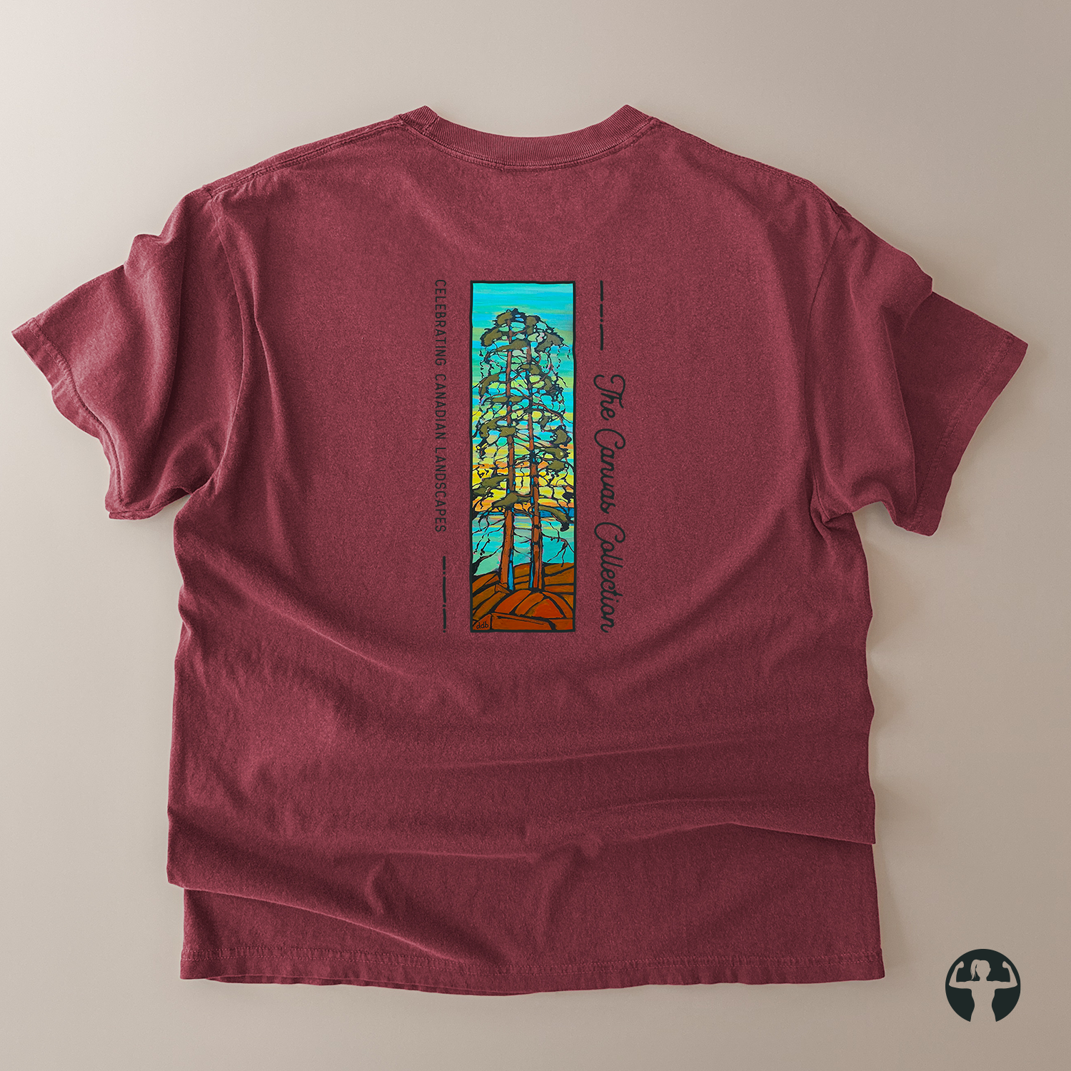 A heathered burgundy t-shirt laid flat on a light beige background, showing the back side with a colorful graphic of a tree and text reading 'The Canvas Collection' and 'Celebrating Canadian Landscapes'.
