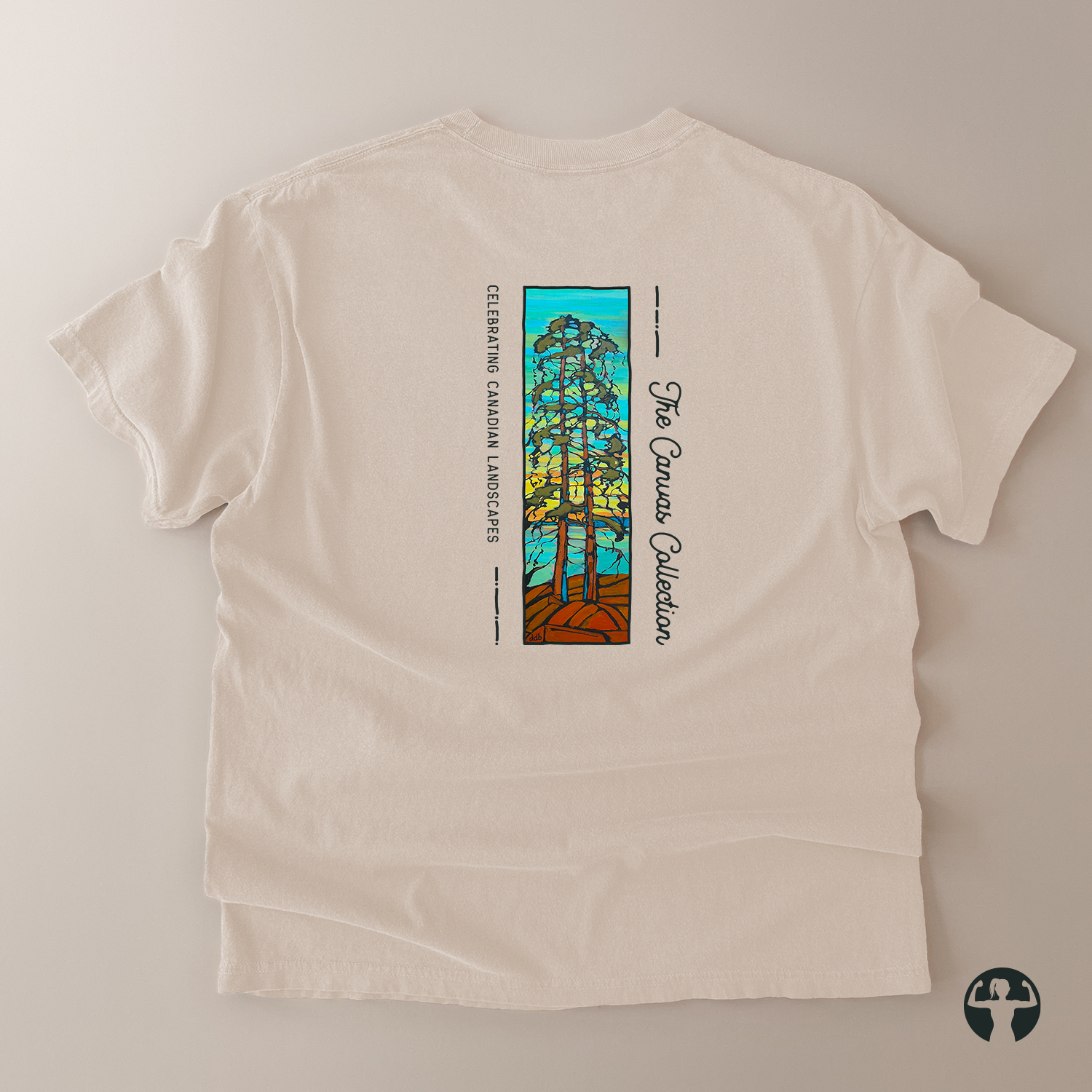 An off-white short-sleeve t-shirt laid flat on a light beige background, showing the back side with a colorful graphic of a pine tree and the text 'The Canvas Collection and 'Celebrating Canada Landscape'.
