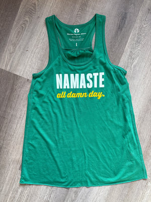 Green tank top with 'Namaste all damn day' text on a wooden floor