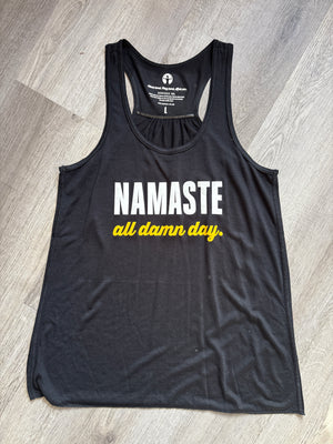 Black tank top with 'Namaste all damn day' text on a wooden floor