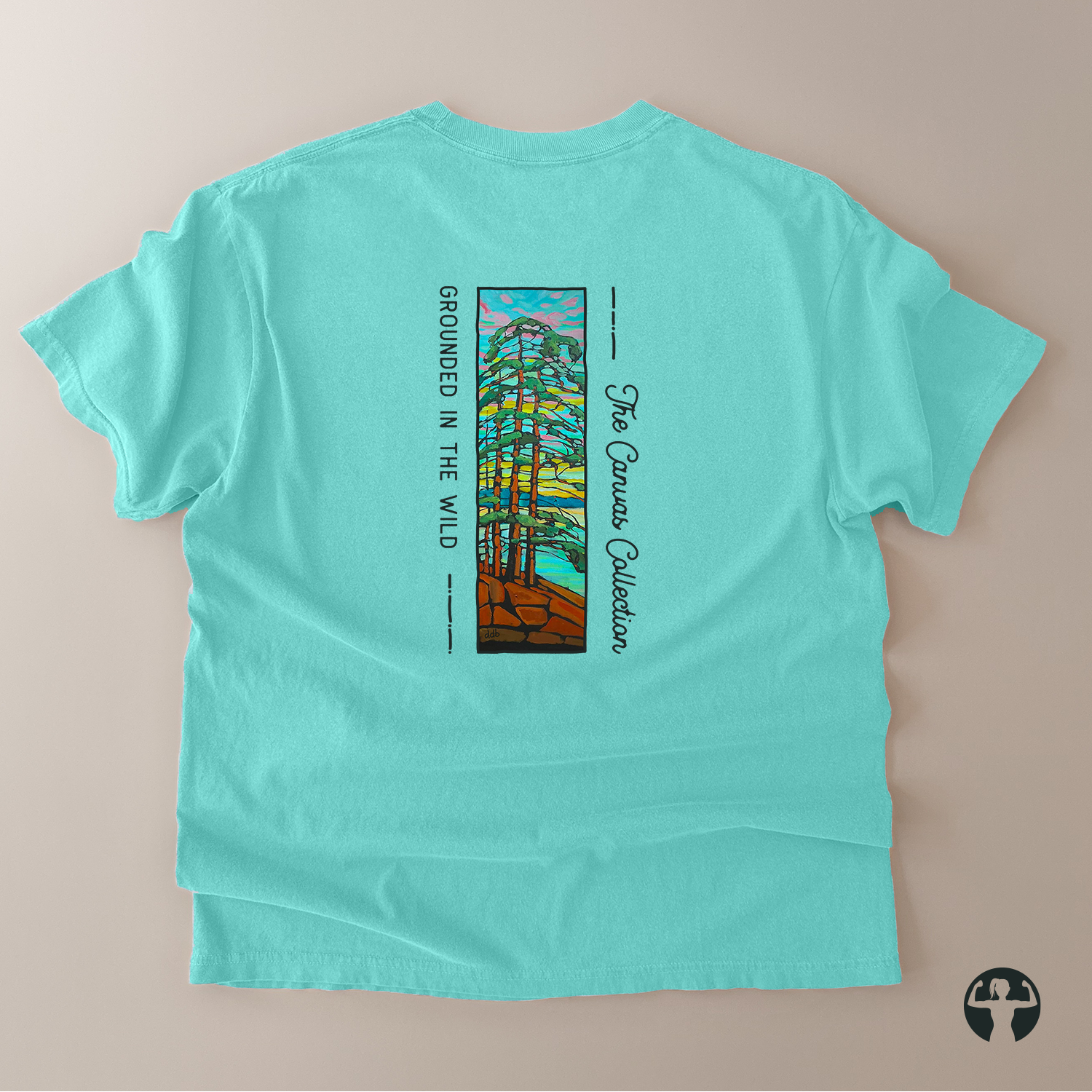 A mint green short-sleeve t-shirt laid flat on a light beige background, showing the back side with a vertical graphic print of a forest and the text 'The Canvas Collection' and 'GROUNDED IN THE WILD'.