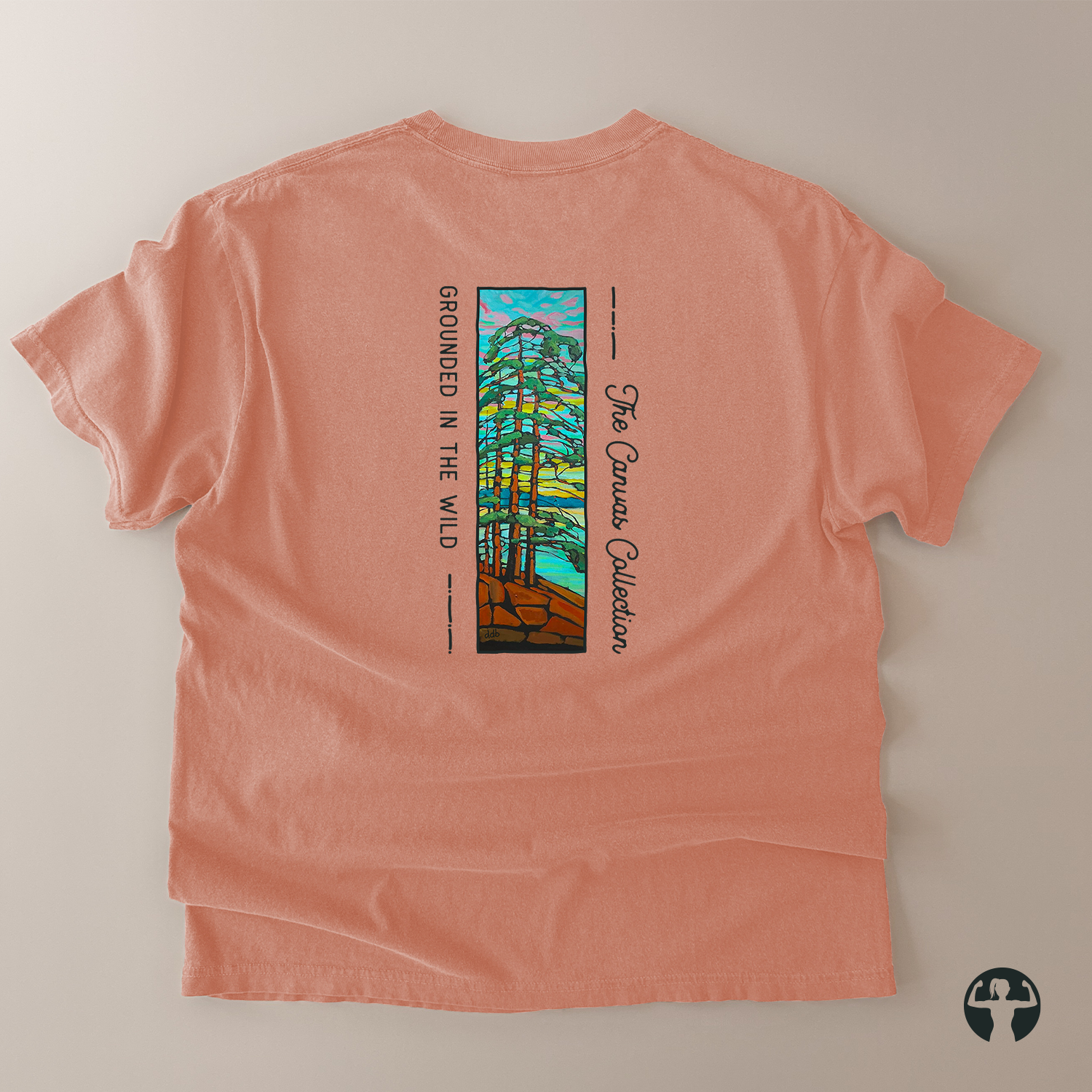 A peach-colored short-sleeve t-shirt laid flat on a light beige background, showing the back side with a vertical graphic print of pine trees and the text 'The Canvas Collection' and 'GROUNDED IN THE WILD'.